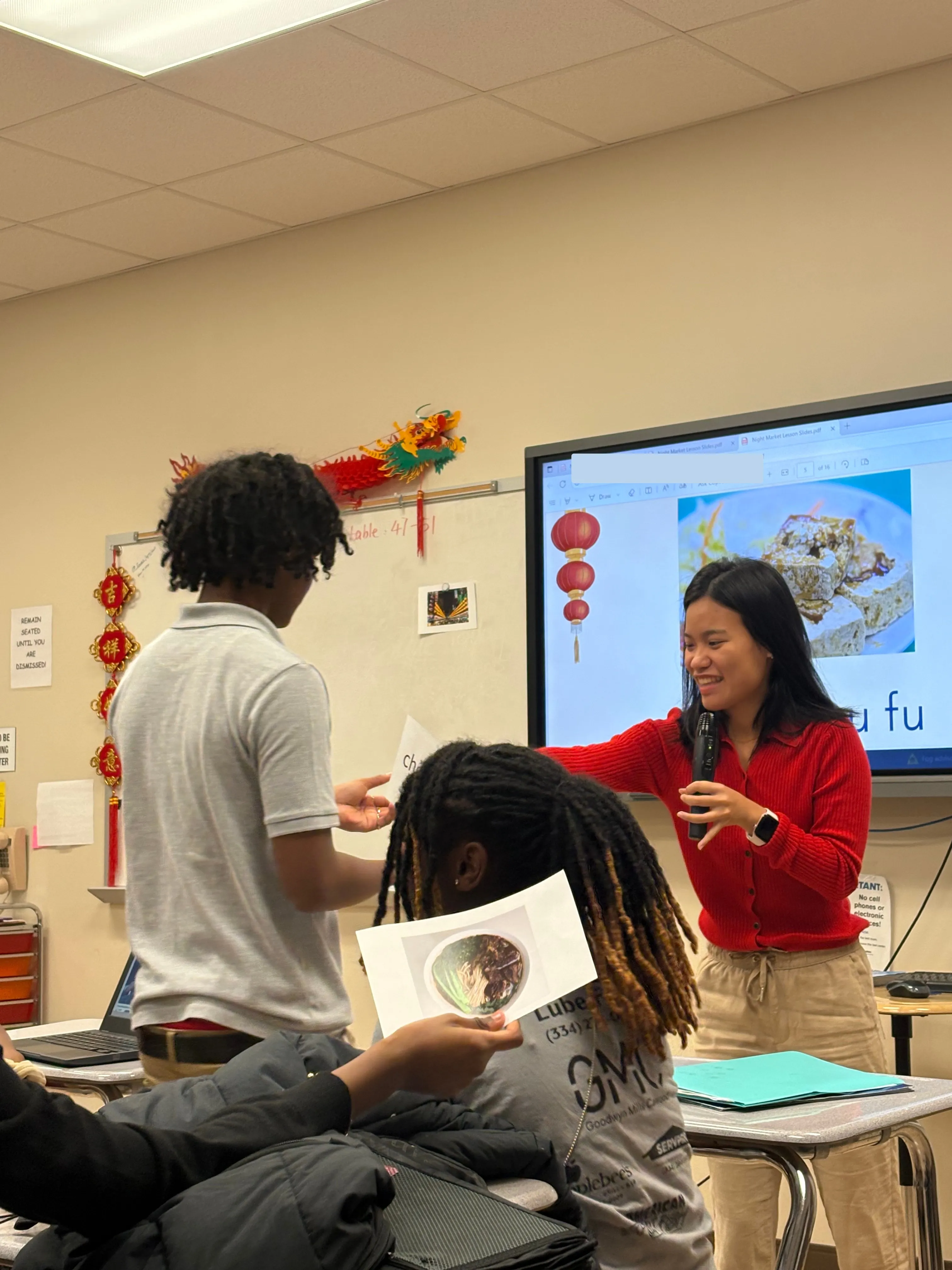 Yi Ling Pan speaks with a student holding a food photograph.